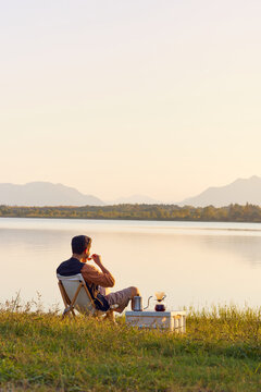 Man Sipping Coffee at Lake Sunset Camping