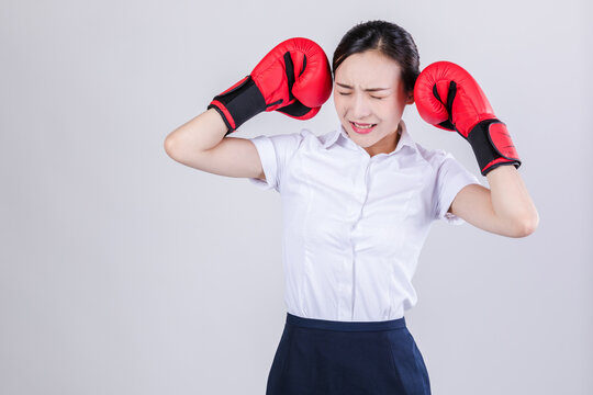 Businesswoman in distress covering ears with boxing gloves