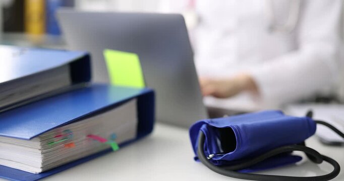 Brightly colored binders sit neatly on a table while a person types on a laptop. This scene highlights the balance of organization and focus in a bright, engaging workspace.