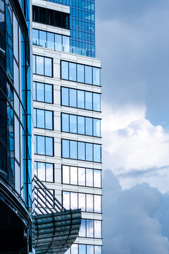 Modern skyscrapers with glass windows and reflective facades rise against a cloudy sky creating layered vertical architecture in a dense urban view