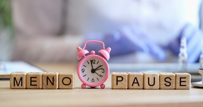 Set in a calm room, wooden blocks spell out MENOPAUSE next to a charming pink clock. This visual explores the significance of menopause in women's health and wellbeing.