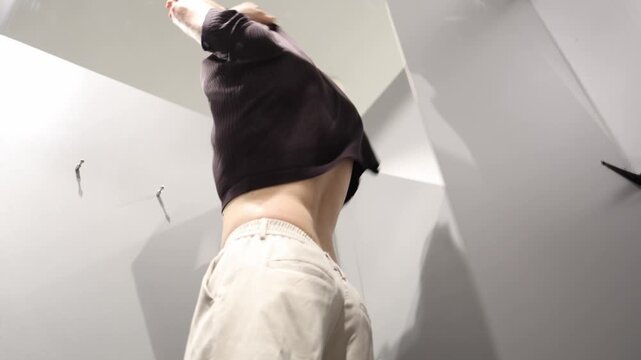 Man dislikes the clothing he tried on and rapidly takes it off before throwing the unwanted old item away showing disappointment frustration and rejection during shopping