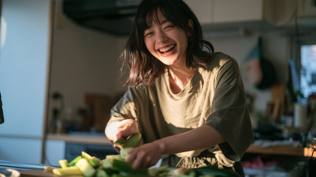 Cheerful Young Woman Laughing While Cooking in Kitchen