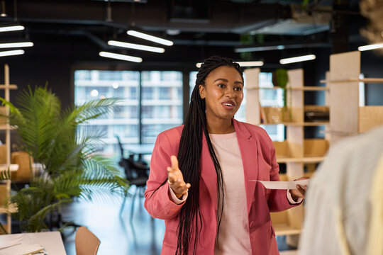 Young curvy black businesswoman talking to colleague at office