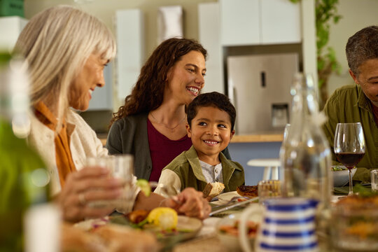 Cute little child sitting on mother's lap at dining table