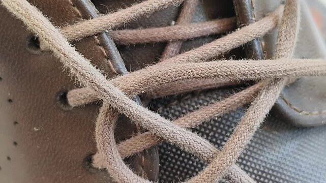 Used and aged brown colour formal shoe lace thread material closeup side view. Footwear fashion concept.