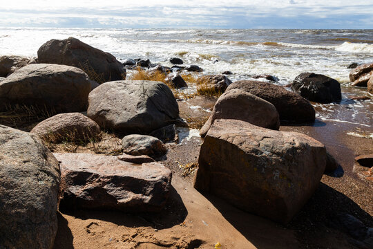 Rocky Beach Seascape With Rolling Waves and Wet Sand Under Blue Sky and Clouds