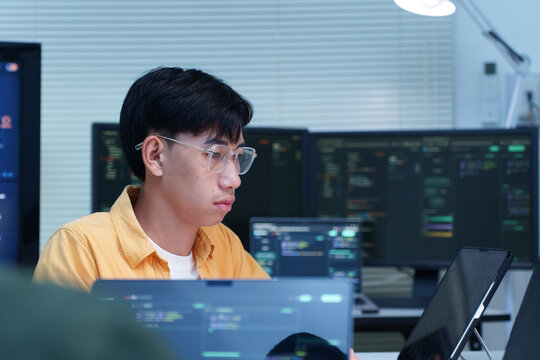 Focused Programmer Writing Code on Multiple Screens