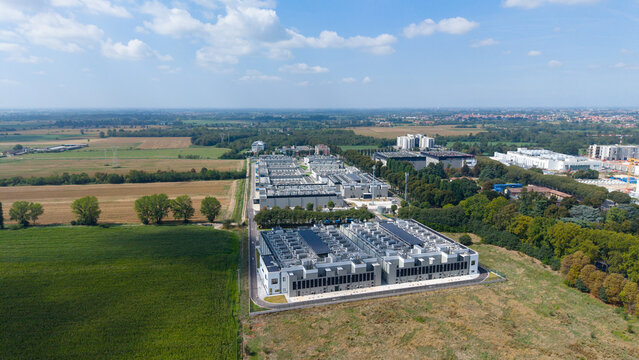 Aerial view of DATA4 MILAN CAMPUS, a modern industrial data center complex surrounded by lush green fields and trees under a clear blue sky in Zona Industriale, Lombardia, Italy.
