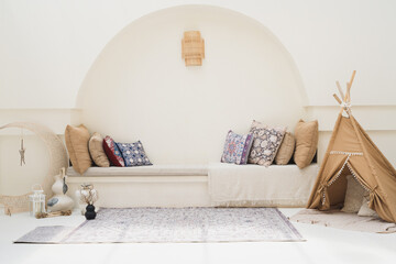 A warm bohemian living room with neutral tones, patterned cushions, textured rug and a small fabric teepee creating a relaxed, cozy atmosphere ideal for family, kids and stylish home decor. © Alfian Muzaki