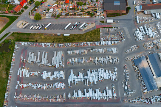 Aerial view of a large industrial stone and paving material storage yard with rows of stacked goods, parked trucks, and paved access roads in Otnice, South Moravian Region, Czechia.