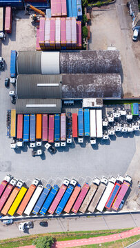 Aerial view of a logistics facility with rows of colorful freight trailers and trucks parked in Cusago, Lombardy, Italy.
