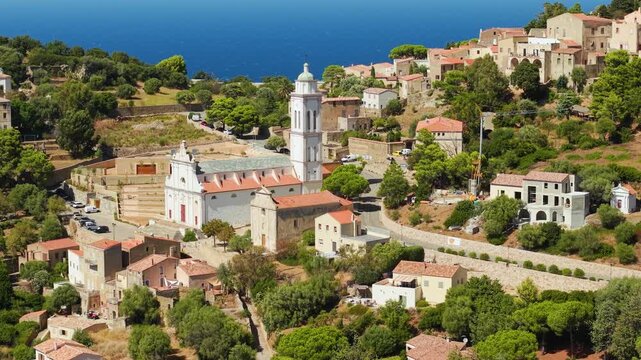 Corbara Corsica France 70mm drone pull back church close up cascading houses sea background authentic village travel destination 4k video