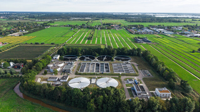 Aerial view of the RWZI Horstermeer wastewater treatment plant with circular tanks and aeration basins surrounded by green fields in Nederhorst Den Berg, Noord-Holland, Netherlands.