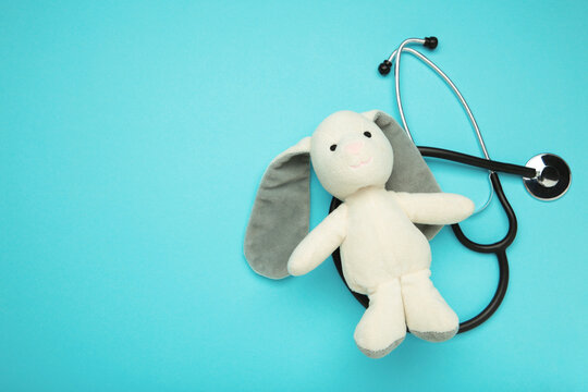 Pediatrician concept. Toy bunny and stethoscope on blue background.