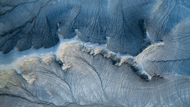 Aerial view of the intricate, eroded badlands and ridges of Factory Butte, showcasing deep gullies and textured sedimentary rock formations in Wayne County, Utah, United States.