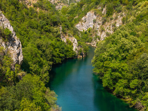 Aerial view of Matka Canyon featuring a deep river gorge with lush green forests, steep limestone cliffs, and calm turquoise water in Skopje, Greater Skopje, North Macedonia.