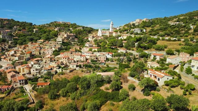 Corbara village Corsica aerial drone view traditional cascaded stone houses perched on hill. Authentic historic Mediterranean town atmosphere with Mediterranean sea and mountains background 4K.