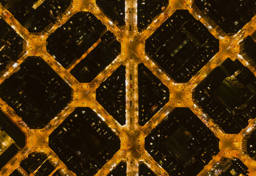 Aerial view of the illuminated grid pattern of Eixample city blocks at night in Barcelona, Catalonia, Spain.