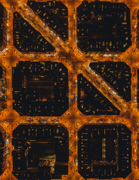 Aerial view of the Eixample district showing the iconic grid pattern of city blocks with chamfered corners illuminated by street lights at night in Barcelona, Catalonia, Spain.