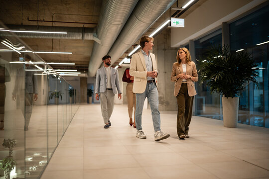 Business colleagues walking office hallway having conversation