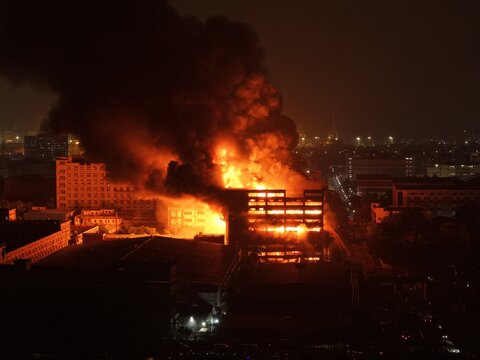 Aerial view of a large industrial building engulfed in flames with thick black smoke rising into the night sky at Chattogram EPZ in Chittagong, Chittagong Division, Bangladesh.