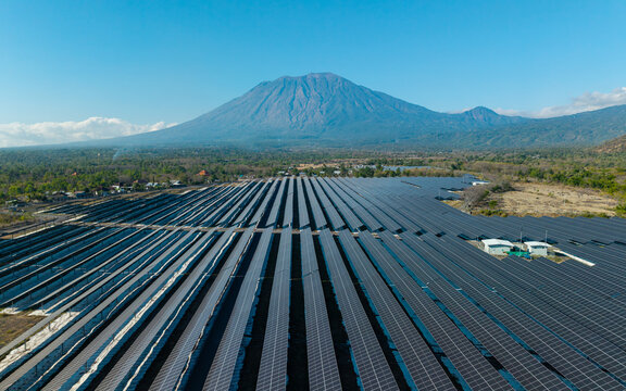 Aerial view of PLTS Medco Solar Bali Timur featuring extensive rows of photovoltaic panels set against the backdrop of Mount Agung in Kubu, Bali, Indonesia.
