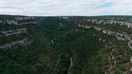 Obraz premium serene and majestic aerial view of forested canyon walls and river above rocky cliffs in natural landscape. Risco los camellos, Cascada de Orbaneja del Castillo