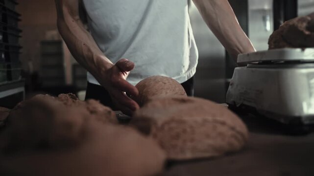 Male Baker hands shaping dough on wooden table for preparation bread and rolls in small bakery kitchen. Working process food industry, artisan craft, traditional method, fresh ingredients