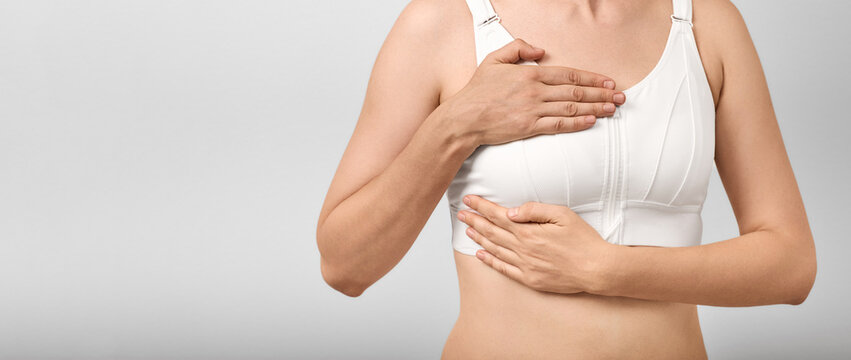 Woman in a white bra examining her breast with both hands. Mastopathy treatment, breast lump screening, and fibroadenoma diagnostics