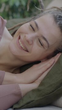 Slow motion portrait of adorable young lady with dreadlocks lying in bed smiling expressing happiness looking at camera. Positive emotion and people concept.