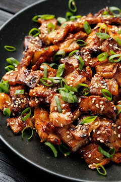 Korean Pork Belly with Sesame Seeds and Green Onions on Black Plate