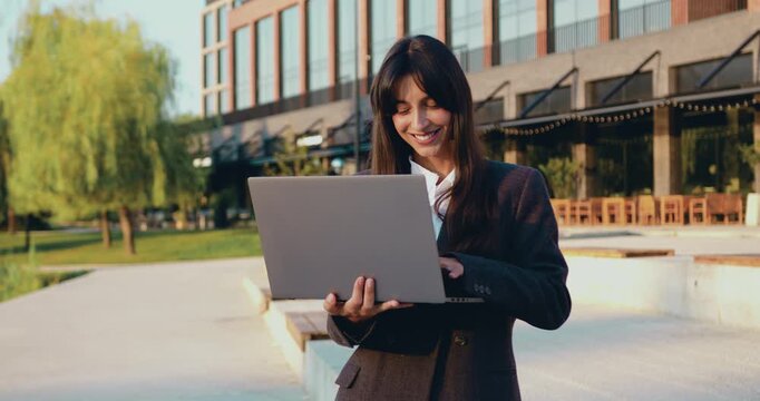 Close up of focused young businesswoman working on laptop outdoors. Beautiful brunette girl making a decision while working on laptop outdoors. People and Technology Concept