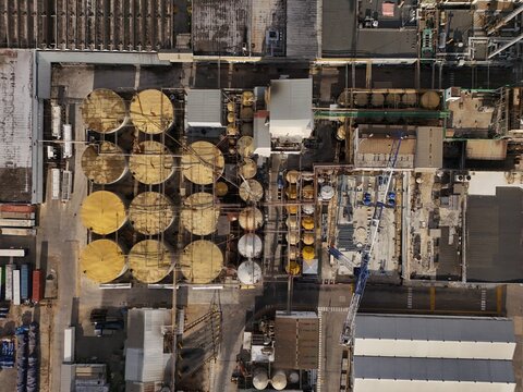 Aerial view of an industrial facility featuring rows of large circular storage tanks, complex piping systems, and construction equipment in Santo Domingo, Distrito Nacional, Dominican Republic.
