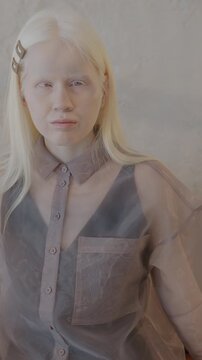 Slow motion portrait of elegant albino lady sitting on couch in luxury apartment looking at camera. Individuality and stylish interior concept.