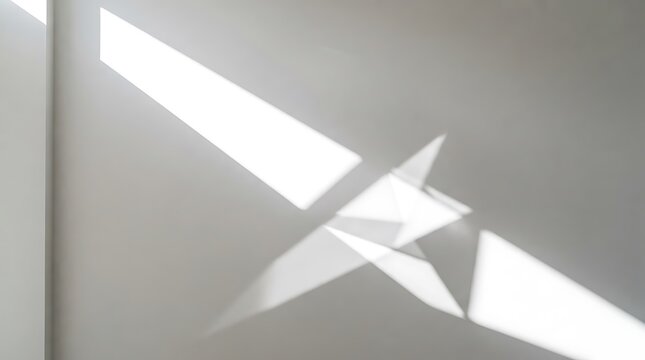 Abstract shadow play on a white wall with geometric shapes and bright sunlight