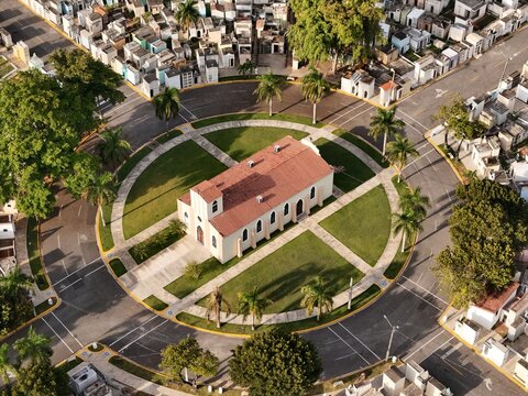 Aerial view of the chapel at Maximo Gomez National Cemetery surrounded by circular roads, lush palm trees, and rows of cemetery plots in Santo Domingo, Distrito Nacional, Dominican Republic.