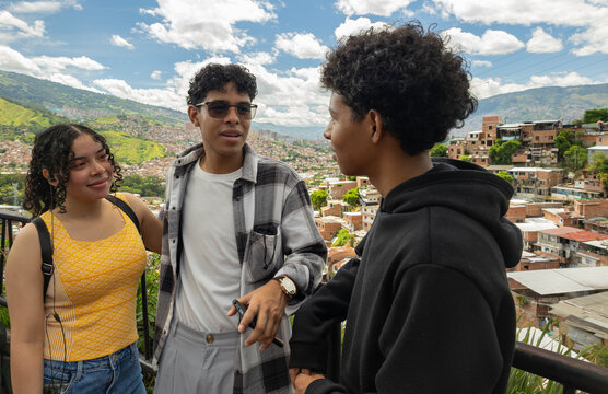 Three young friends enjoying a sightseeing visit at a viewpoint in San Javier, Medell&iacute;n, Colombia, while observing the urban surroundings
