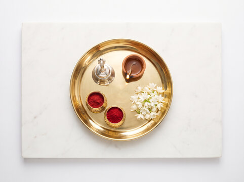Traditional Indian Pooja Thali with Brass Plate, Kumkum, Diya Oil Lamp, and Jasmine Flowers on Marble Background