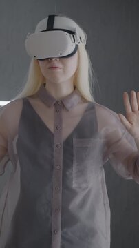 Slow motion of young woman wearing virtual reality glasses enjoying new experience indoors in apartment. Wearable VR device and modern technology concept.