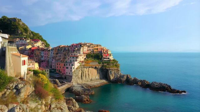Colorful cliffside village overlooking a turquoise cove and open sea in clear daylight. Travel promotion, tourism advertising, and travel documentaries.