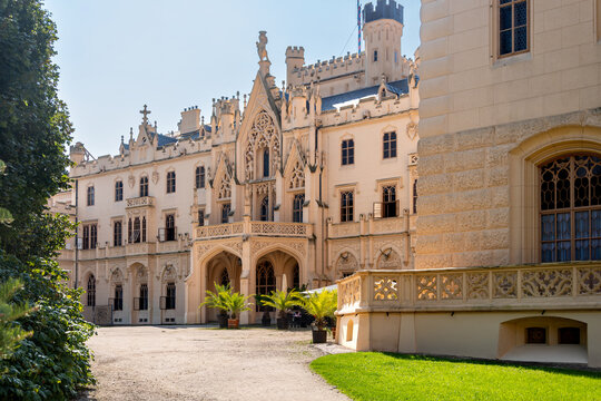 A view of Lednice Castle in the Czech Republic. A neo-Gothic castle in Moravia surrounded by a park. A historic park and garden in summer. Flowering plants in the park.