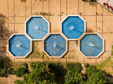 Aerial view of a hexagonal fountain complex with blue water basins set in a tiled plaza surrounded by green trees, Varna, Varna, Bulgaria.
