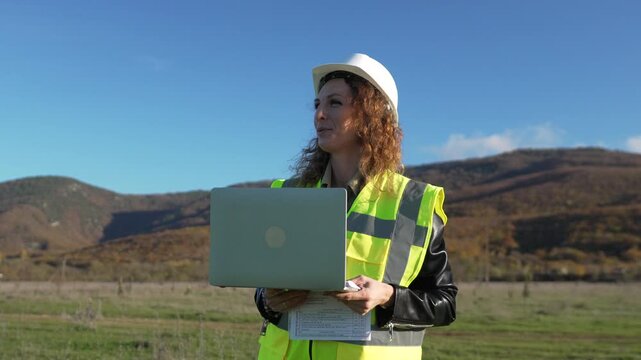 Engineer safety construction worker woman discussing site survey report data outdoors in the mountains holding a laptop.