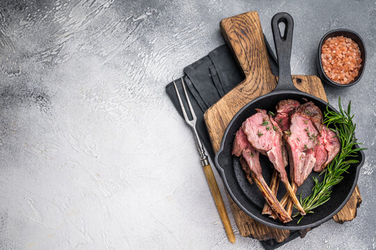 Roast lamb chops, mutton meat cutlets in a skillet. grey background. top view