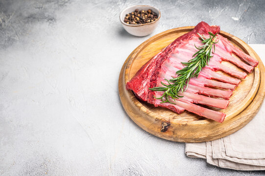 Uncooked rack of lamb, raw mutton chops on wooden board. grey background. top view