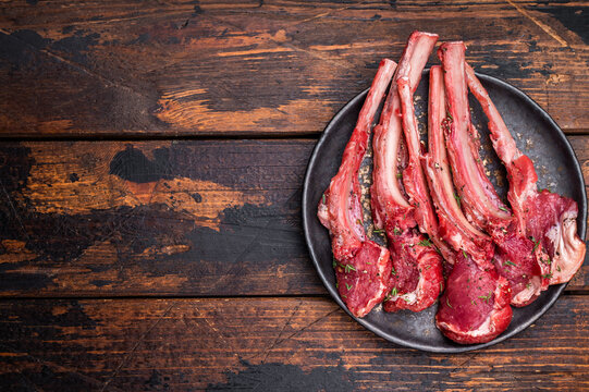 Raw lamb chop cutlets, fresh mutton meat for steaks with herbs. wooden background. top view