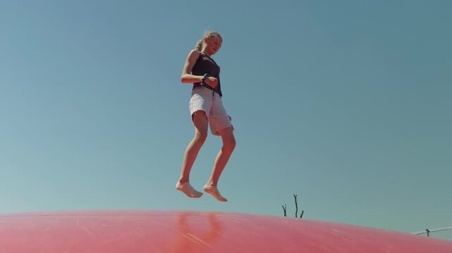 A girl does the splits while jumping the sky in the background
