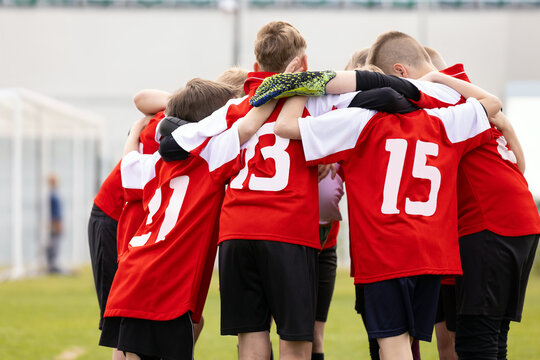 Youth Soccer Team in Red Jerseys 13 and 15 Gathering in Tight Pre-Match Huddle - Children Football Team Unity and Strategic Briefing on Field
