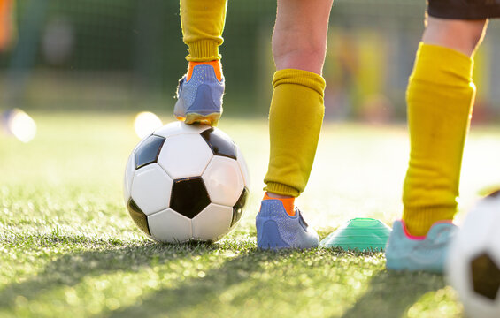 Close-Up of Junior Player Foot in Bright Cleat Resting on Soccer Ball During Training Session - Youth Football Skill Drill on Green Pitch